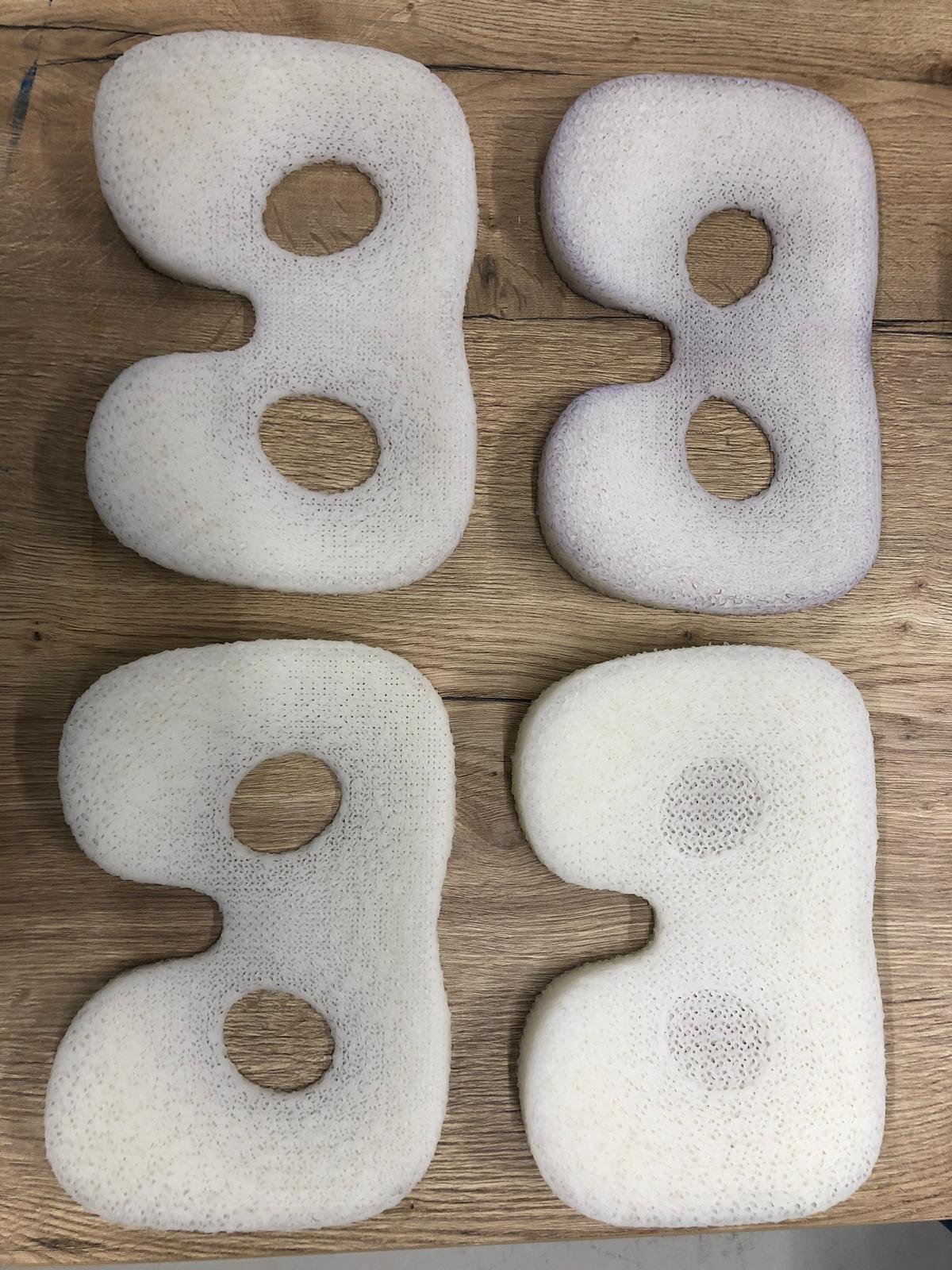 Vier witte SLS-nylon zittingkernen met open lattice-structuur op een houten tafel